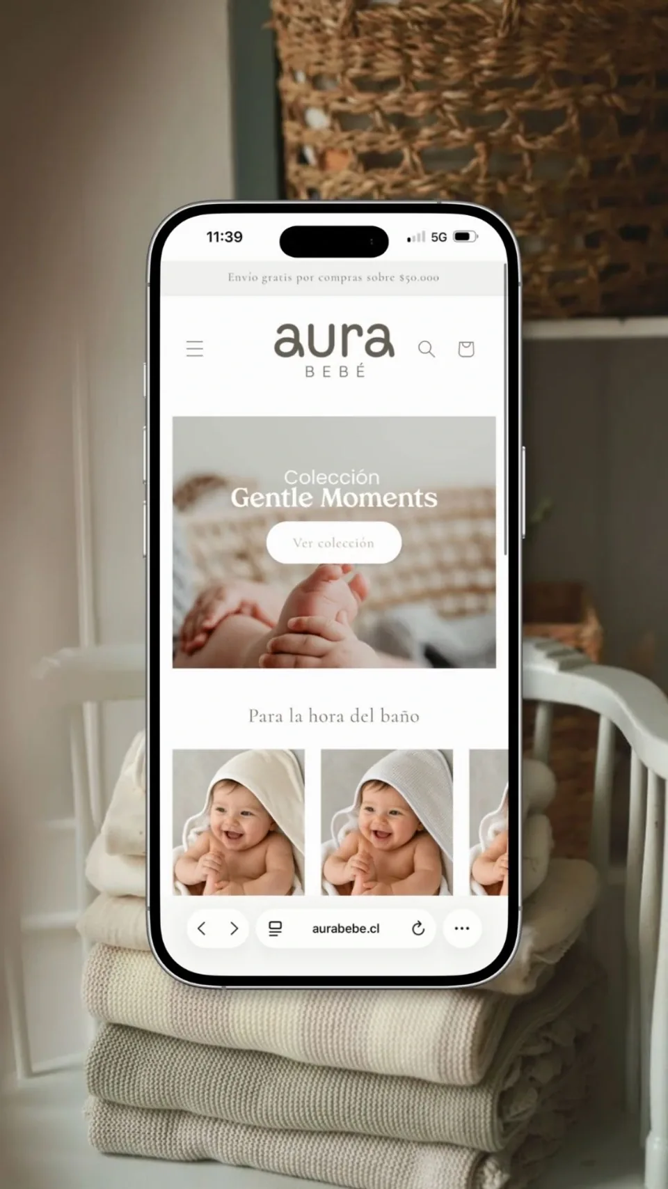 Tienda en línea de Aura Bebé en un teléfono apoyado sobre mantas dobladas en una cuna