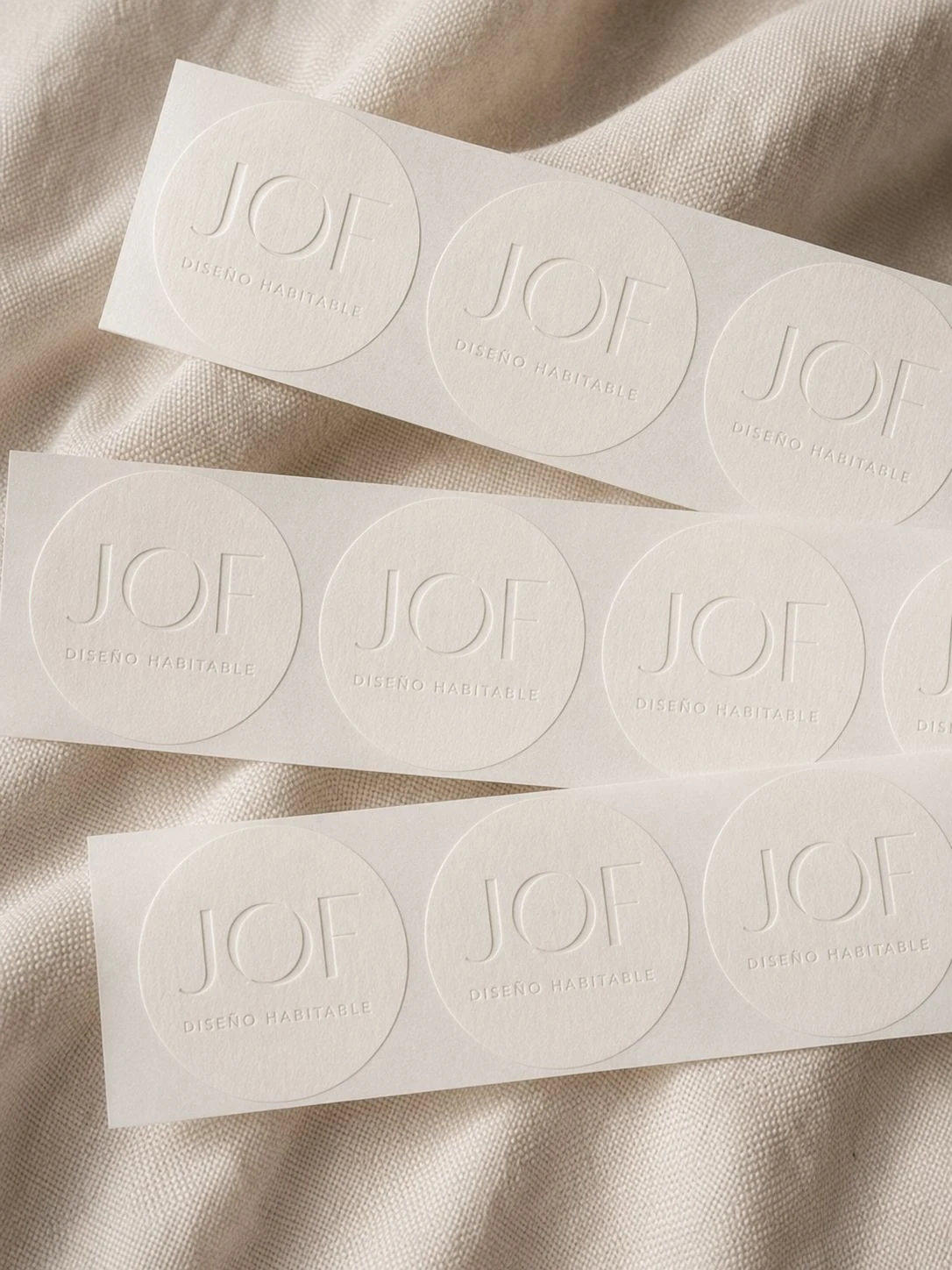 Adhesivos circulares de JOF grabados en seco sobre papel color crudo