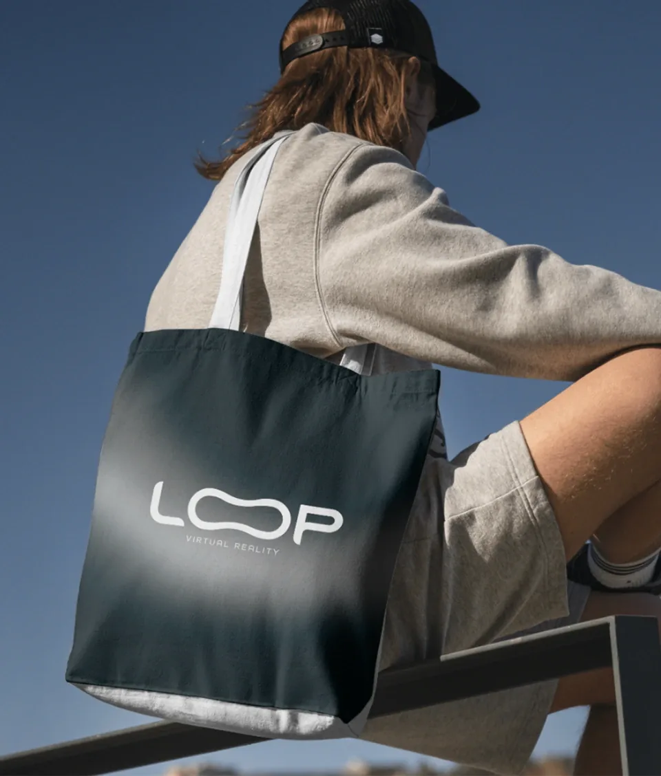 Bolsa de tela negra con el logotipo de Loop, colgada del hombro de una persona sentada