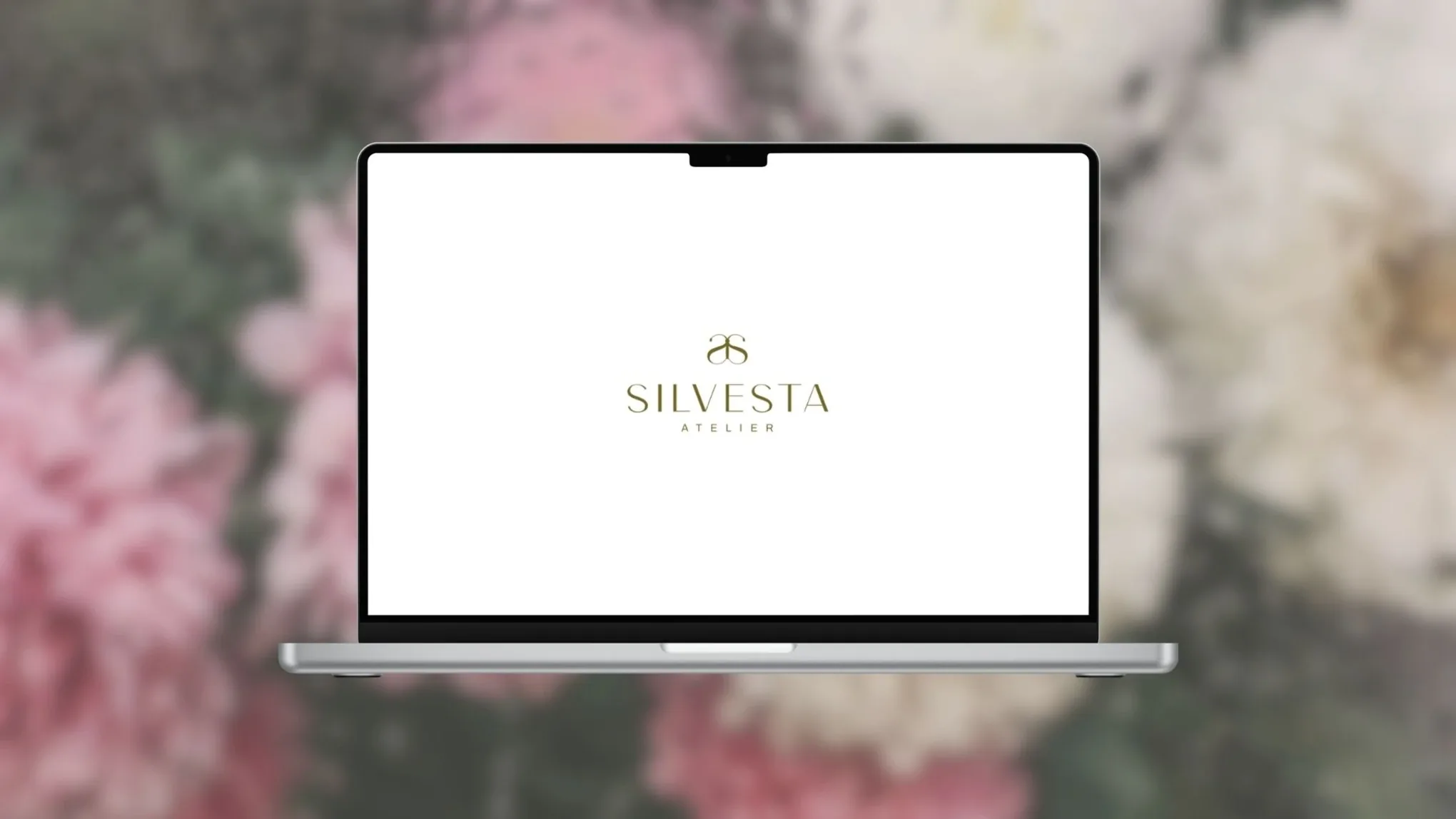 Logotipo de Silvesta Atelier en la pantalla de un portátil, sobre un fondo de flores rosadas desenfocadas