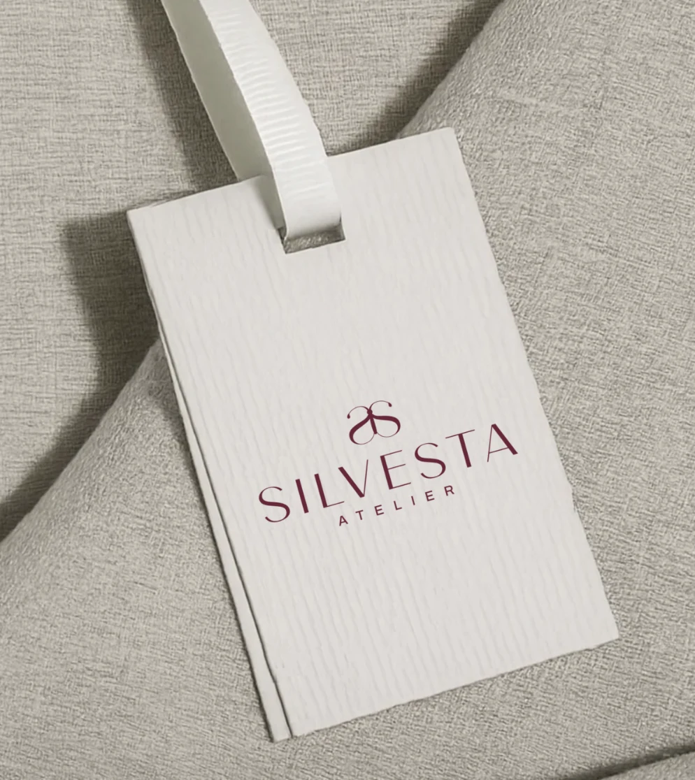 Etiqueta colgante de tela con el logotipo de Silvesta Atelier impreso en vinotinto