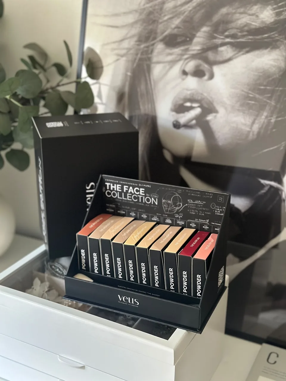 Exhibidor The Face Collection de Veus con la línea completa, sobre una cómoda blanca