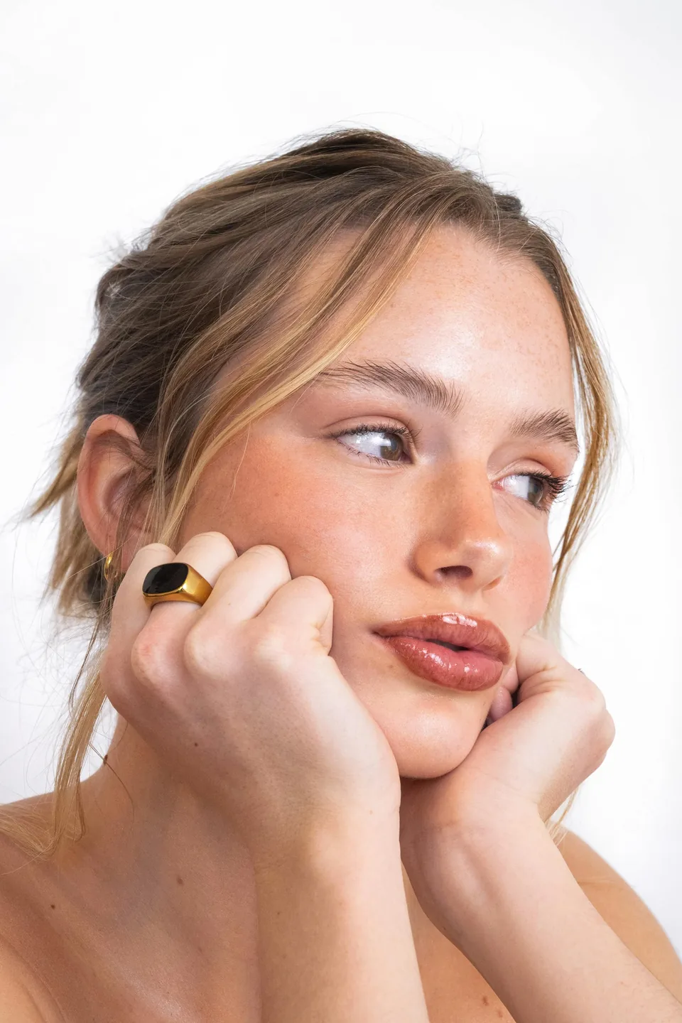 Mujer con maquillaje natural apoyando el mentón en la mano, con la piel luminosa