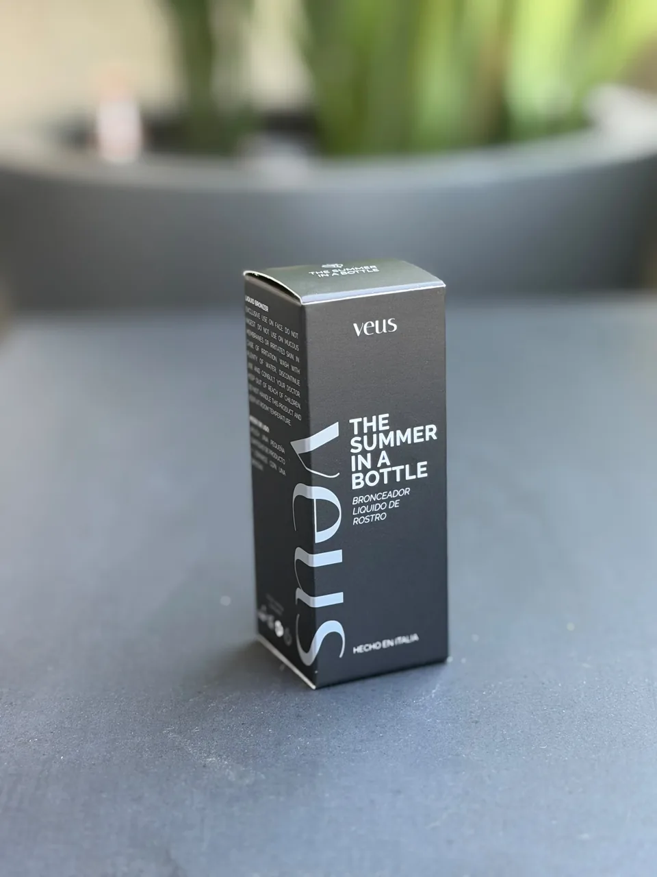 Caja negra del producto The Summer in a Bottle de Veus, sobre una mesa gris
